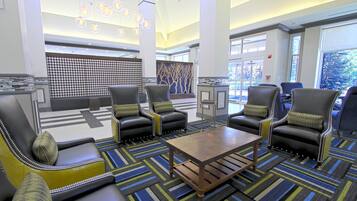 A lobby with leather armchairs, a coffee table, and a patterned carpet.
