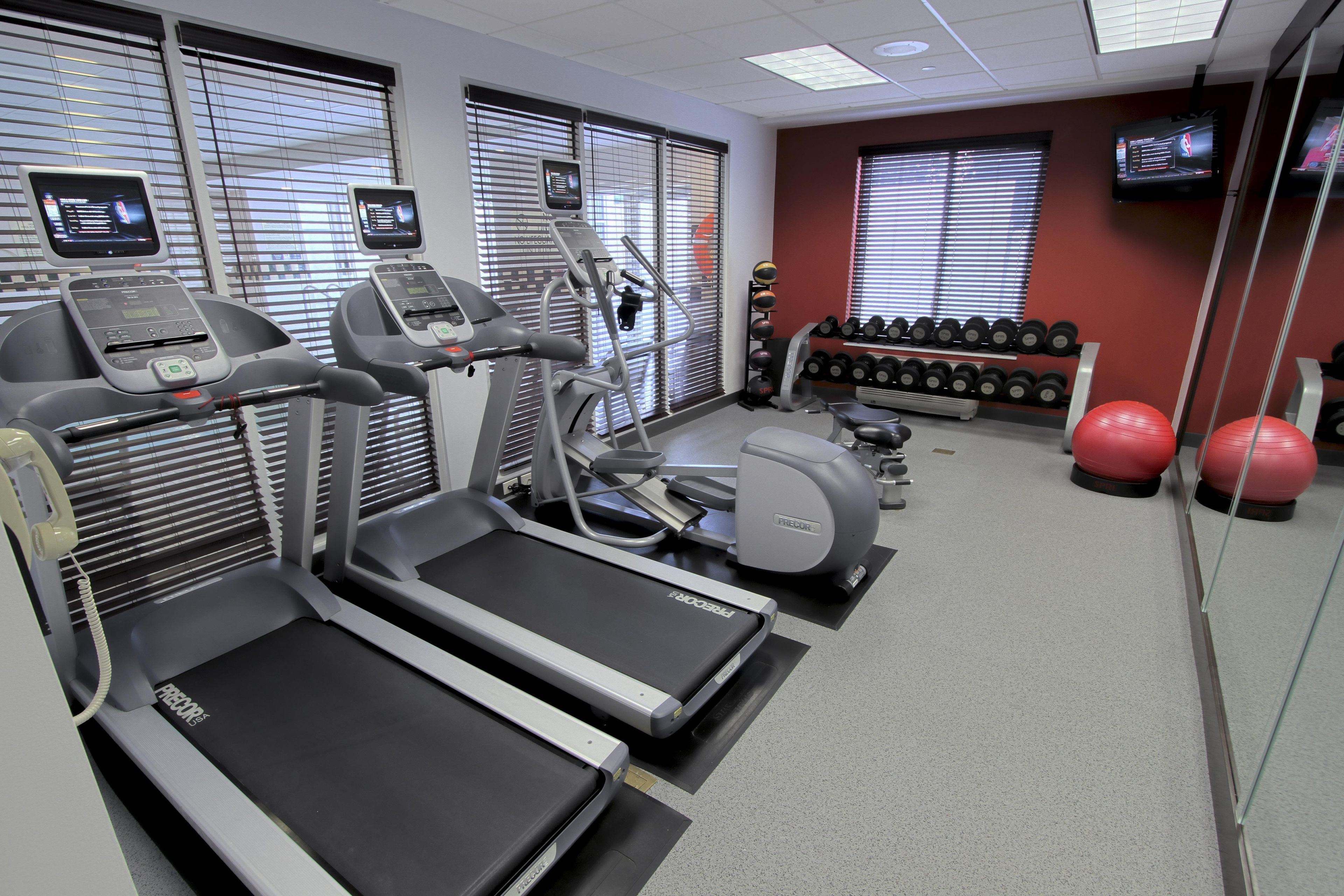 A gym with treadmills, a weight bench, and a rack of dumbbells.