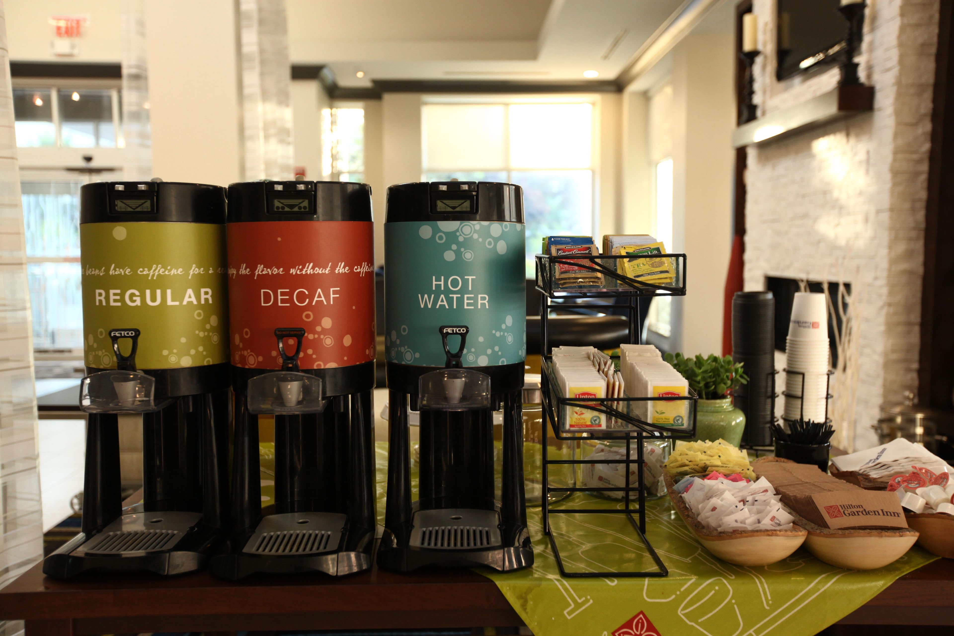 Una estación de café con tres máquinas de café diferentes etiquetadas como 'Regular', 'Descafeinado' y 'Agua Caliente'.