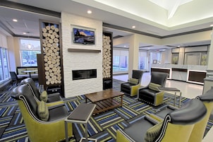 A modern lobby with a fireplace, seating area, and a television.