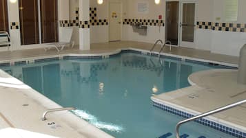 An indoor swimming pool with clear lane markings, a lifeguard chair, and a poolside area with a tiled floor.