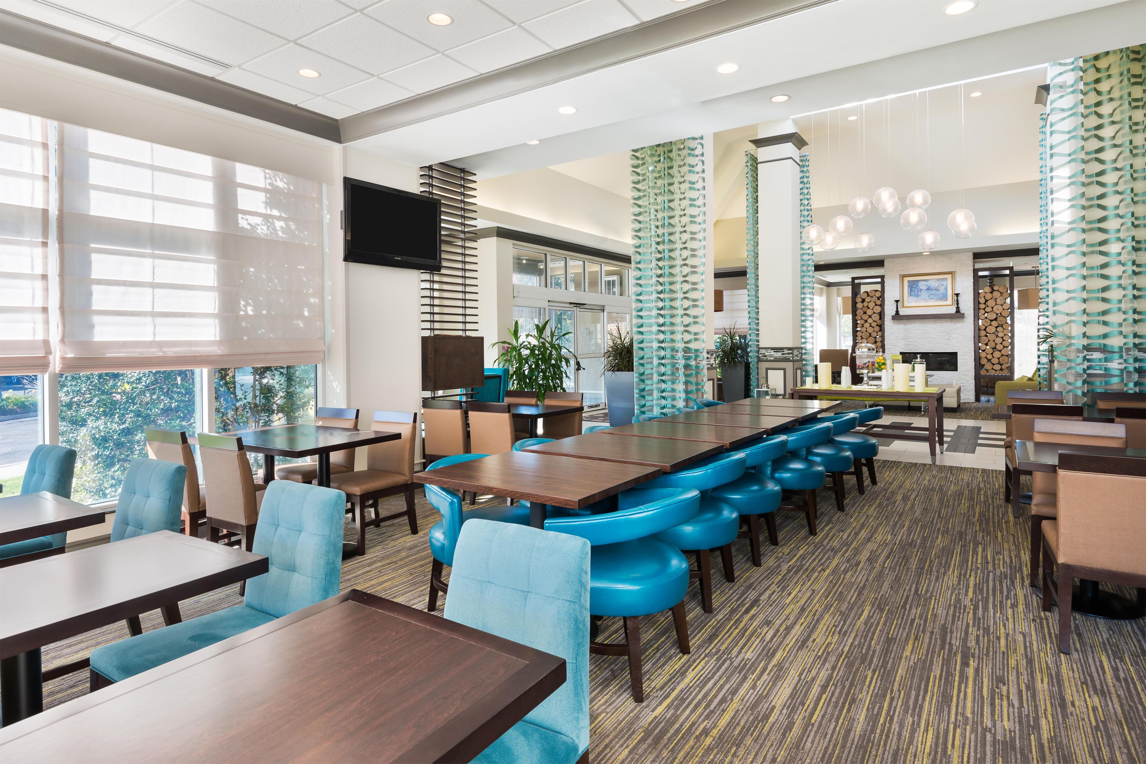 A hotel dining area with multiple tables and chairs, a bar area, and a fireplace.