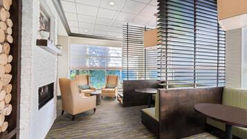 A modern interior with a fireplace, seating area, and large windows.