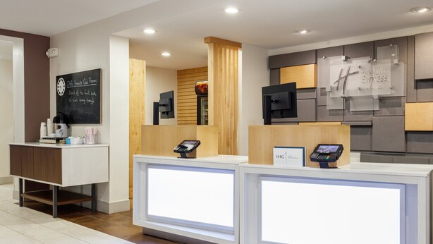A hotel reception area with two reception desks, a chalkboard with a message, and a Holiday Inn Express sign. - Holiday Inn Express & Suites Newport News by IHG (Newport News)