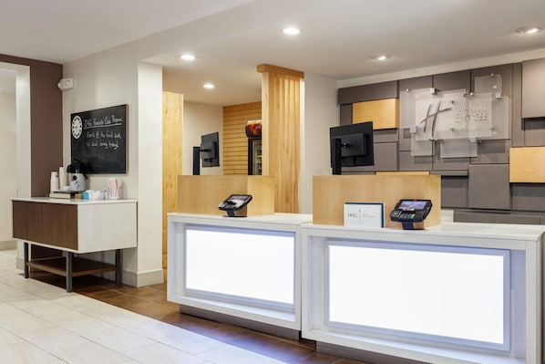 Een hotel receptie met twee balies, een schoolbord met een bericht, en een Holiday Inn Express bord.