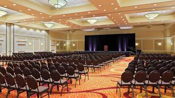 Un salón de conferencias amplio con filas de sillas y un escenario.