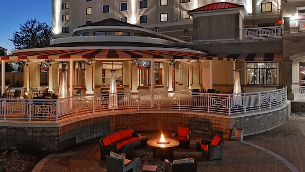 A hotel lobby with a curved outdoor seating area, a fire pit, and a pool.