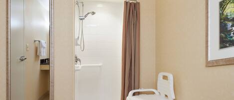 A bathroom with a shower, a toilet, and a mirror.
