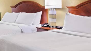 A hotel room with two beds, a wooden headboard, a bedside table with a lamp, and a telephone.