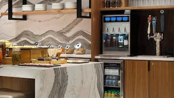 A modern kitchen with marble countertops, a wine station, and a variety of glassware and dishes.