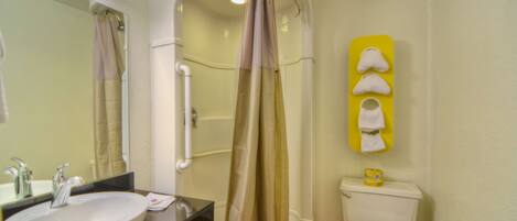 A bathroom with a sink, mirror, shower curtain, toilet, and towel rack.