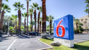 A motel sign with the number 6, surrounded by palm trees and a parking lot. - Motel 6 Palm Springs, CA - East - Palm Canyon (Palm Springs)