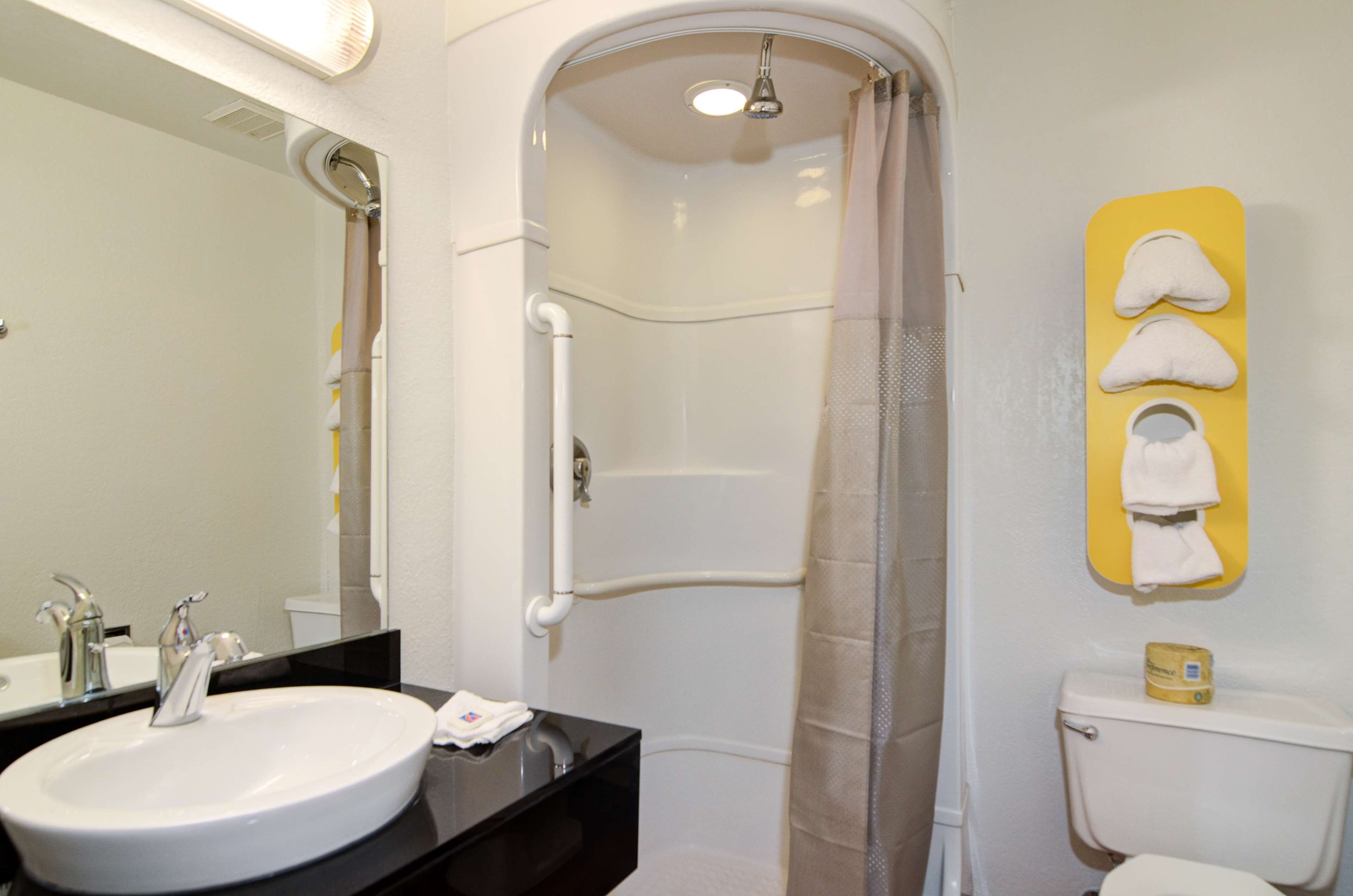 Een badkamer met een wit wastafel, spiegel, douche en toilet.