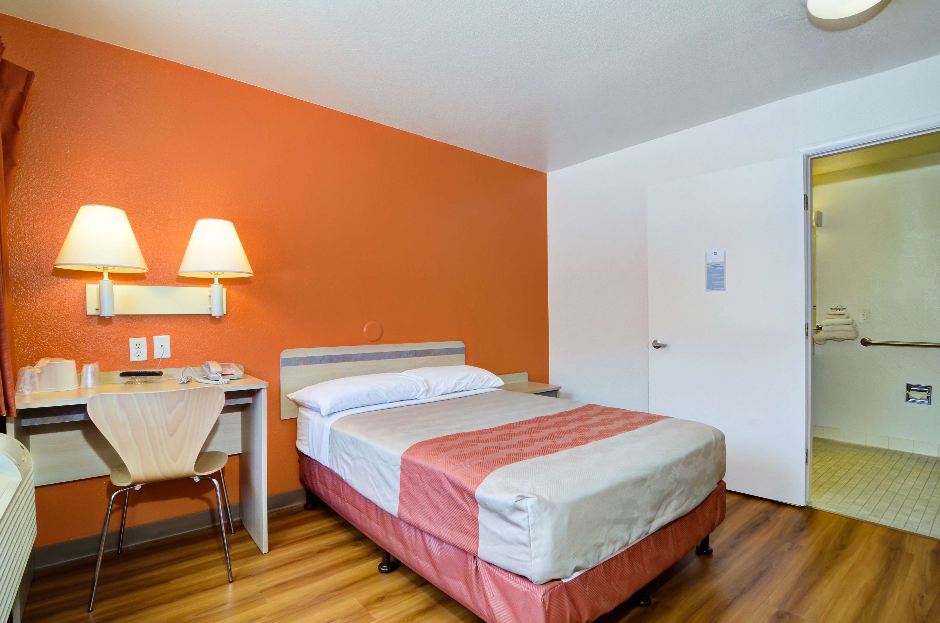 Une chambre d’hôtel équipée d’un lit, d’un bureau, d’une chaise et de deux lampes fixées au mur.