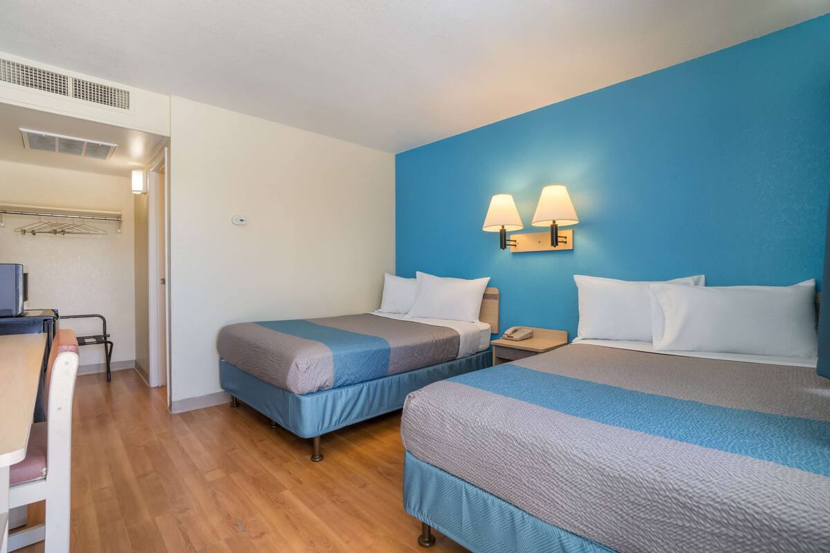 A hotel room with two beds, a desk, and a chair.