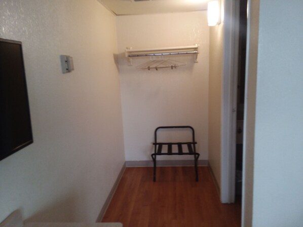 A narrow hallway with a wooden floor, a black metal rack, and a white wall-mounted drying rack.