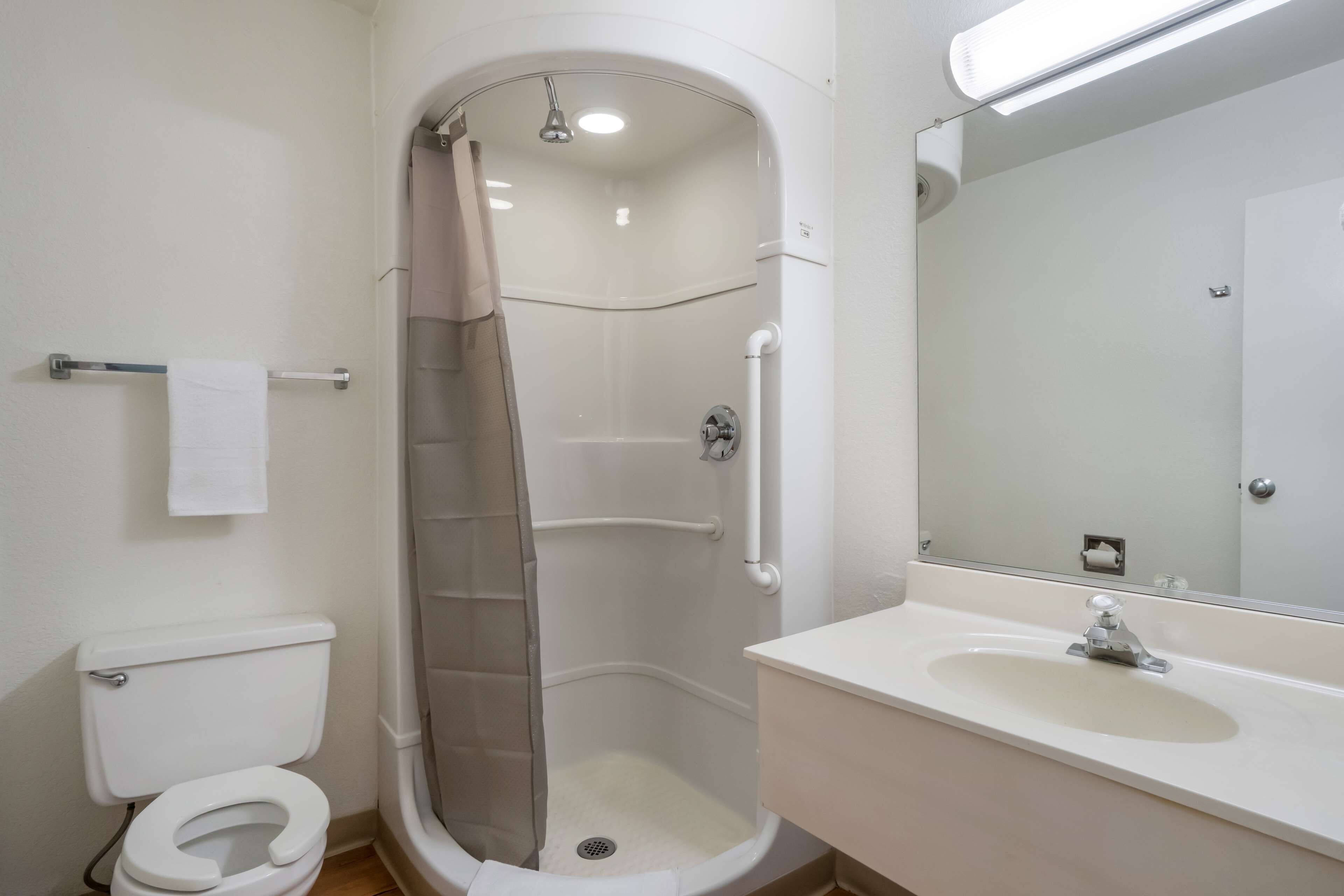 Un baño moderno con cabina de ducha, inodoro y lavamanos con espejo.