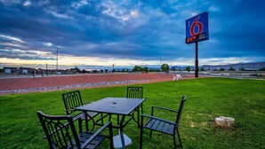 A grassy area with a table and chairs, a sign indicating '6 WIFI HERE', and a road in the background. - Motel 6 Grand Junction, CO (Grand Junction)