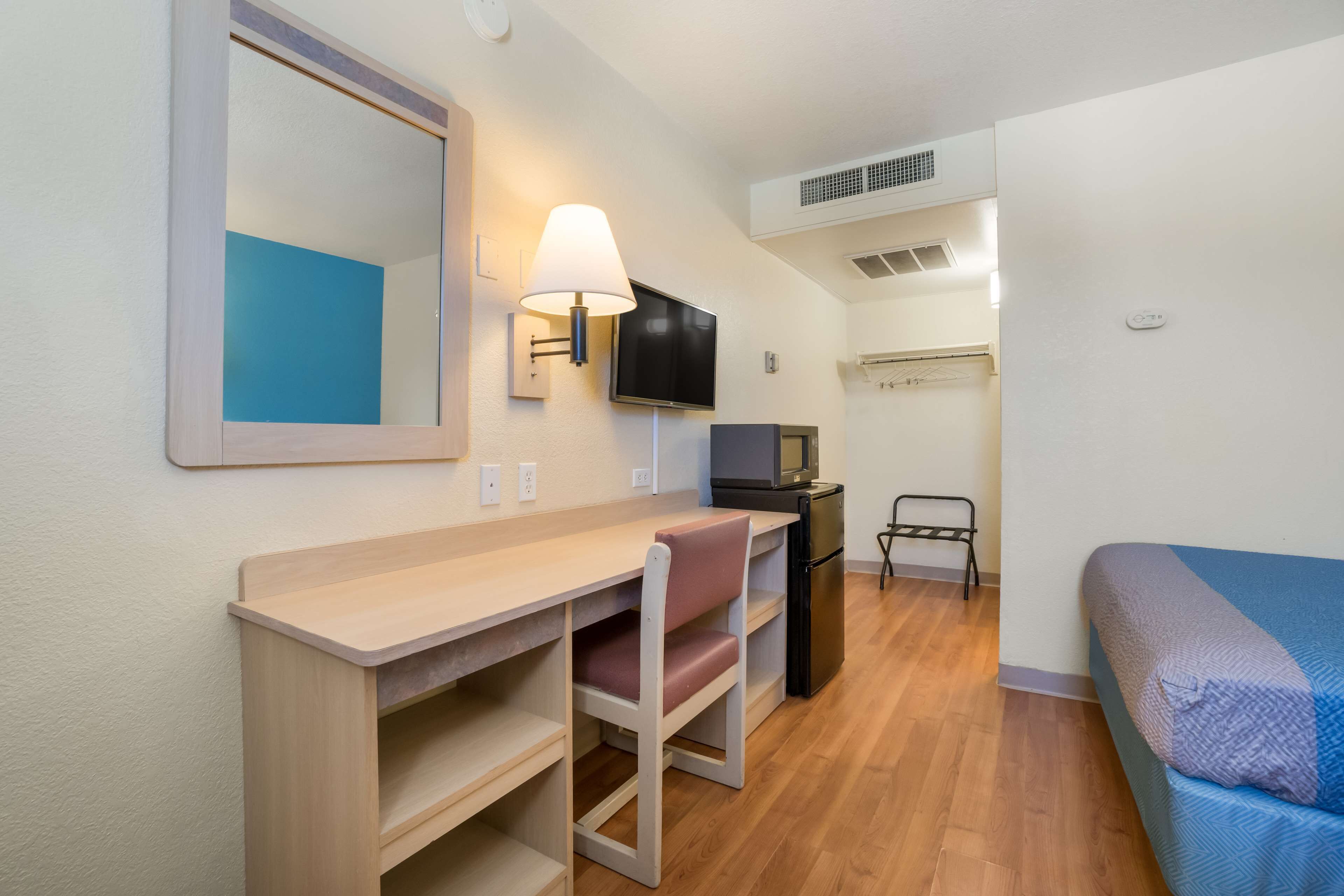 A compact room with a desk, chair, TV, and bed.