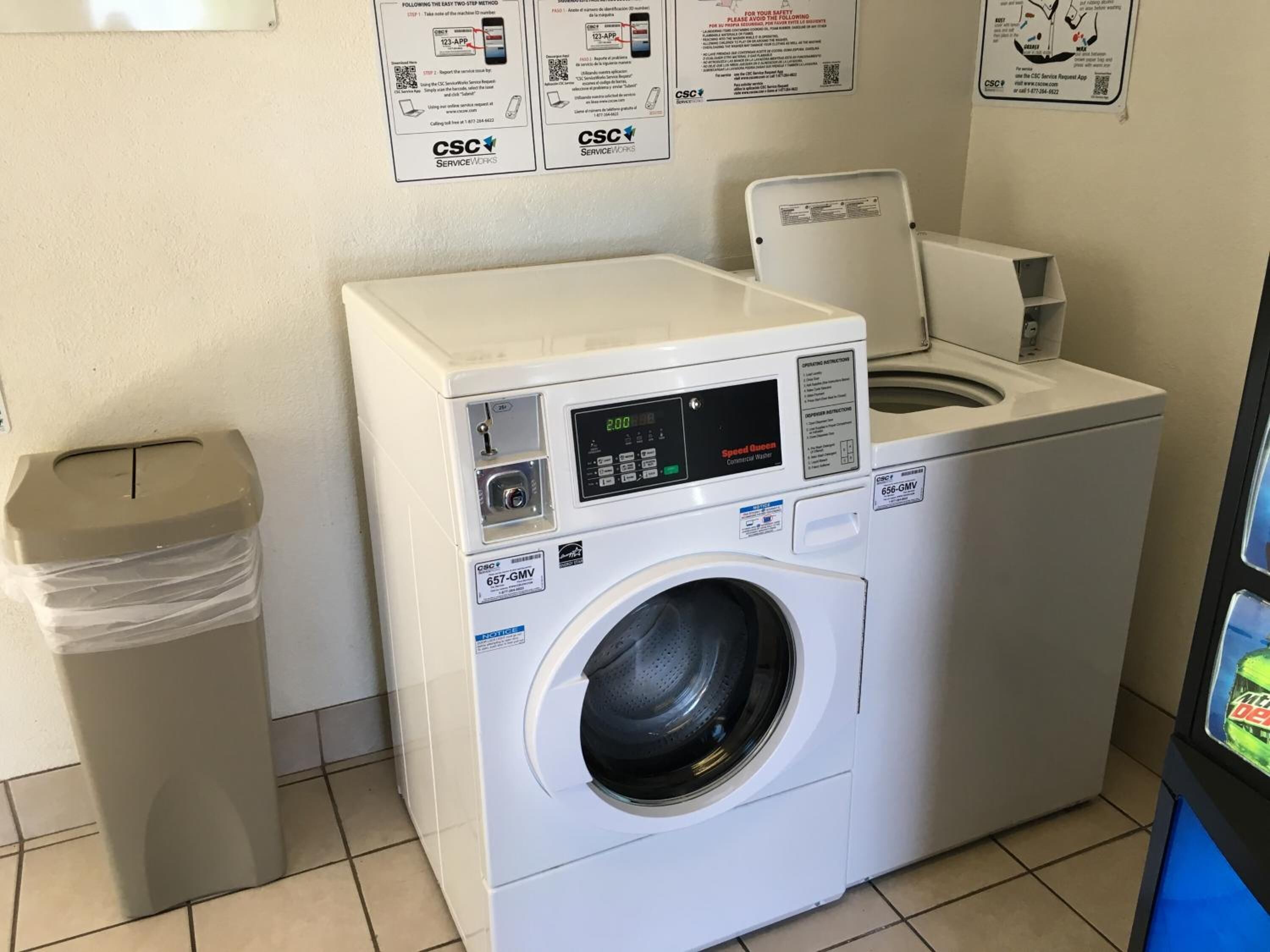 A front-loading commercial washer with a digital display, a control panel, and a front-loading dryer.