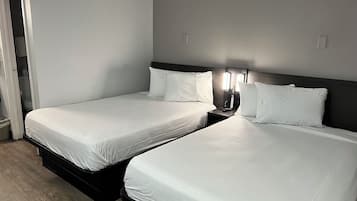 A hotel room with two single beds, a nightstand with a lamp, and a wardrobe.