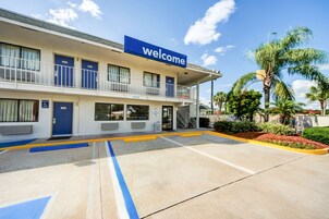 Un hotel con un cartel de 'Welcome', estacionamiento accesible y entrada cubierta.