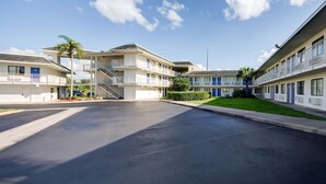 Una hilera de edificios de motel con balcones, un paseo central y cielo despejado.