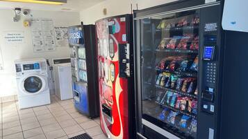A laundromat with a vending machine, a washing machine, and a dryer.