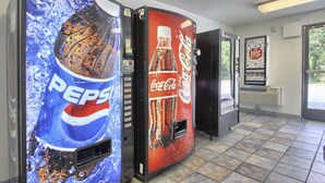 Dos máquinas expendedoras de bebidas, una de Pepsi y otra de Coca-Cola, en un espacio comercial con suelo de baldosas y una puerta que da al exterior.