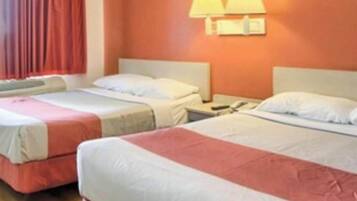 Een hotelkamer met twee enkele bedden, een nachtkastje met een lamp en een raam met gordijnen.
