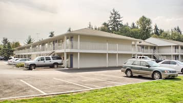 Un motel composé d’un bâtiment à deux étages, d’un parking où sont garées plusieurs voitures et d’une zone herbeuse en premier plan.
