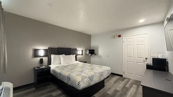 Een hotelkamer met een bed, nachtkastjes, een bureau, een stoel, een televisie en een deur.
