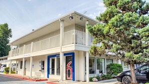 A motel with a two-story structure, a balcony on the upper floor, and a '6' sign indicating the room number. - Motel 6 Seattle, WA - South (SeaTac)