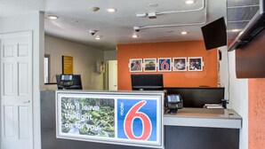 A motel reception desk with a large sign reading "We'll leave the light on for you." - Motel 6 Seattle, WA - South (SeaTac)