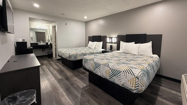 A hotel room with two beds, a desk, a mirror, and a bathroom visible through an open door. - Motel 6 Seattle, WA - South (SeaTac)