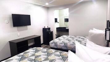 A hotel room with two beds, a TV, a desk, and a mirror.