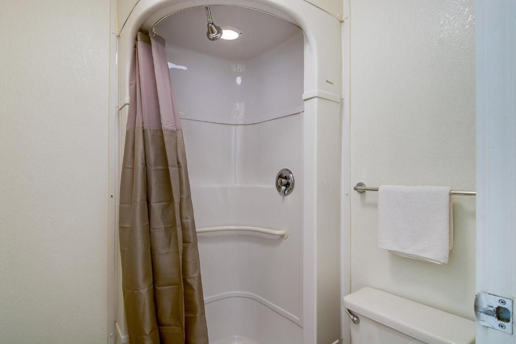 Un baño con cabina de ducha, inodoro y toallero.