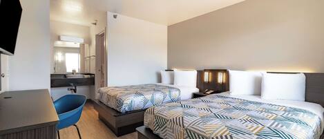 A hotel room with two beds, a desk, a chair, and a TV.