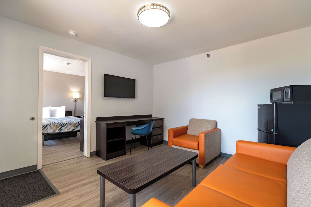 A modern hotel room with a bed, a desk, a television, and a microwave.