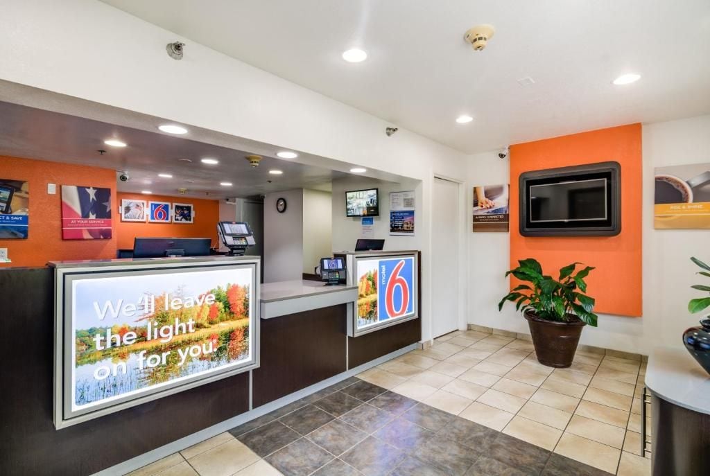 A reception area with a counter, a television screen, and a potted plant.