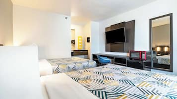 A hotel room with two beds, a desk with a TV, a microwave, and a mirror.