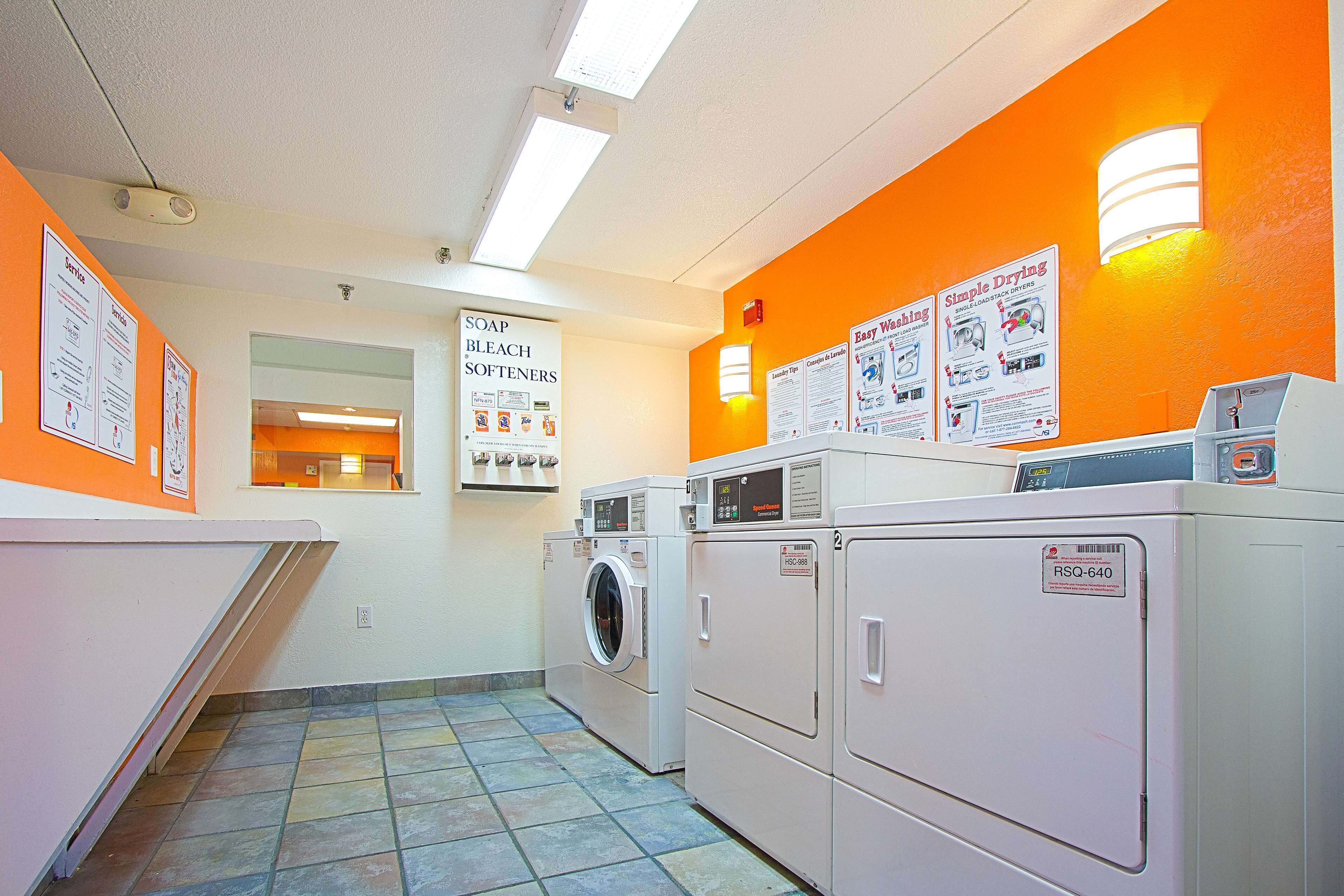 A laundry room with washing machines, dryers, and instructional posters on the walls.