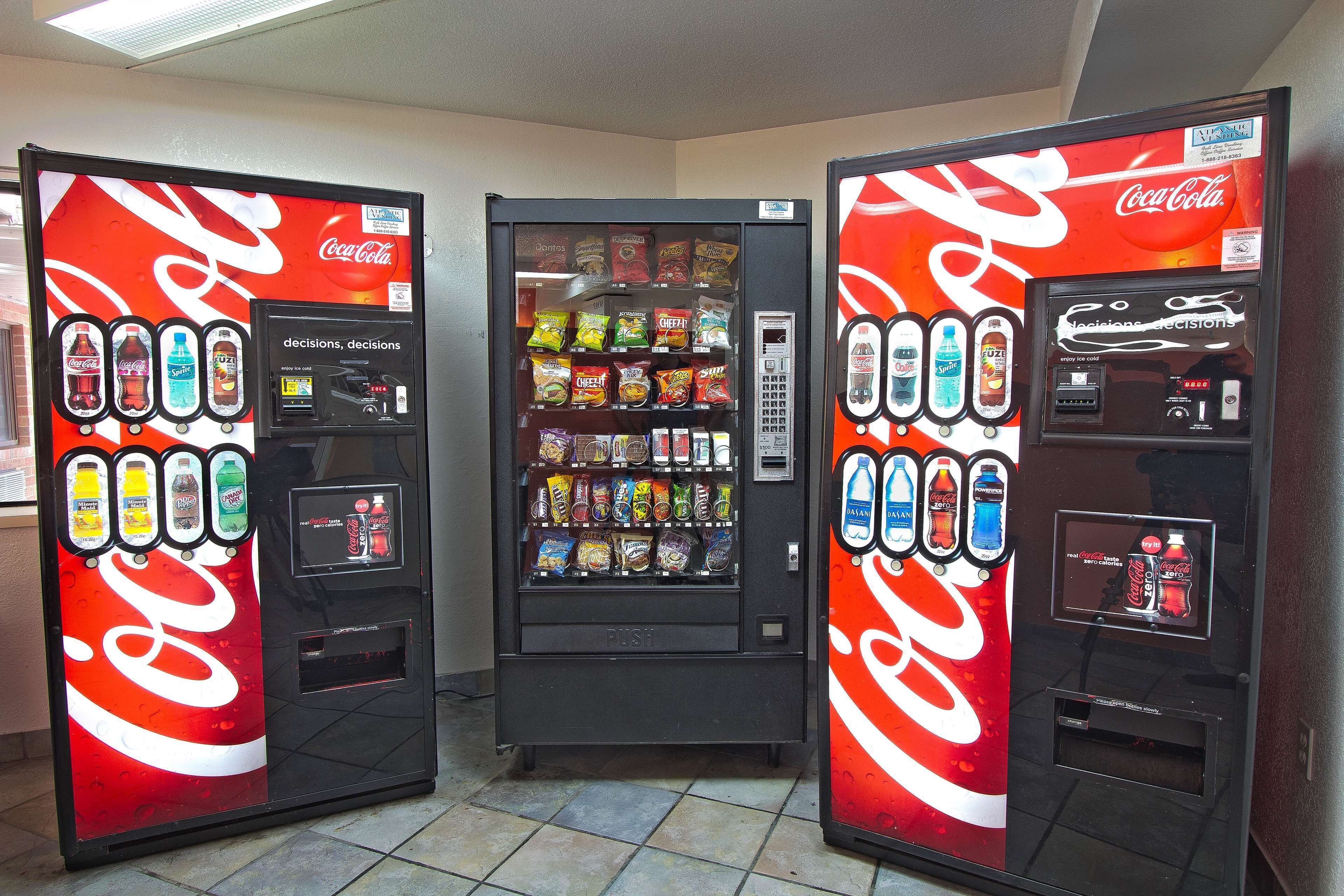 Three Coca-Cola vending machines with various beverages and snacks.