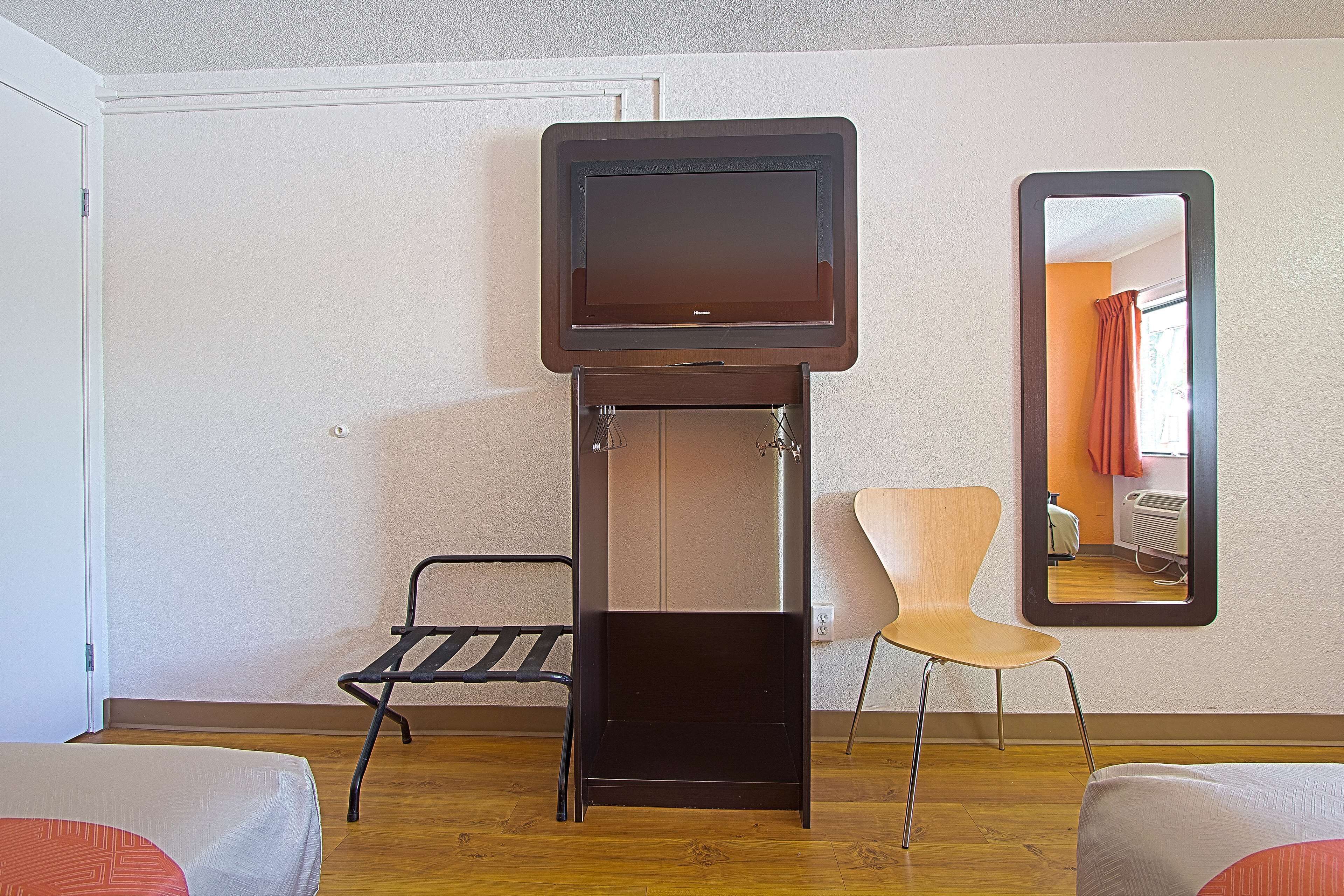 Habitación pequeña con un atril plegable para la televisión, una silla y una cama.