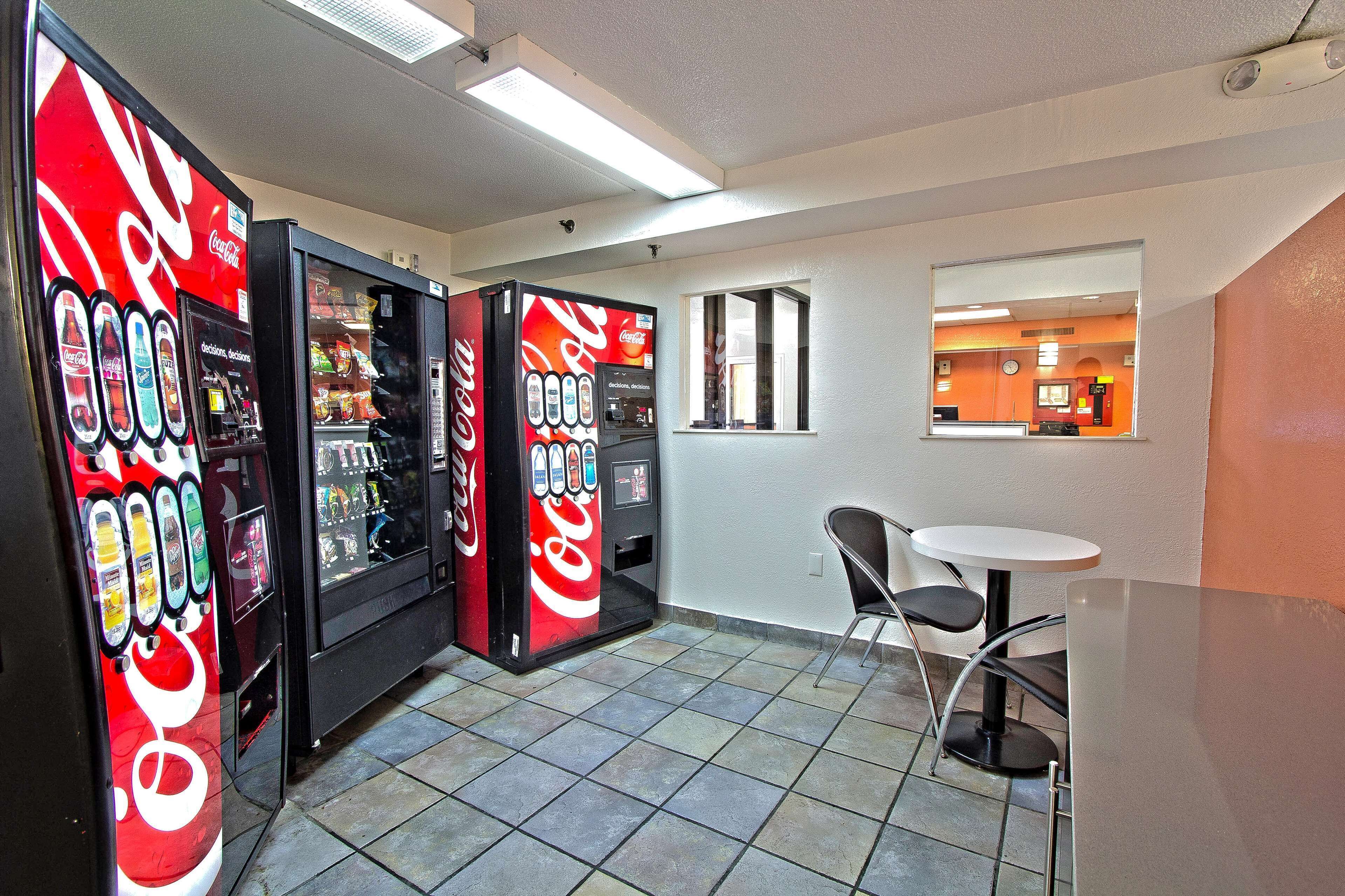 Una stanza con due distributori automatici di Coca-Cola, un tavolino e una sedia.