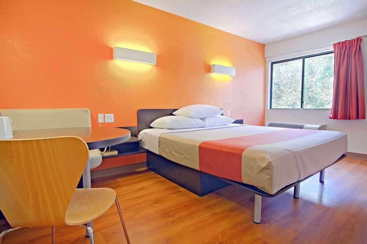Habitaci ón de hotel con cama, una silla, una mesa y una ventana con cortinas.