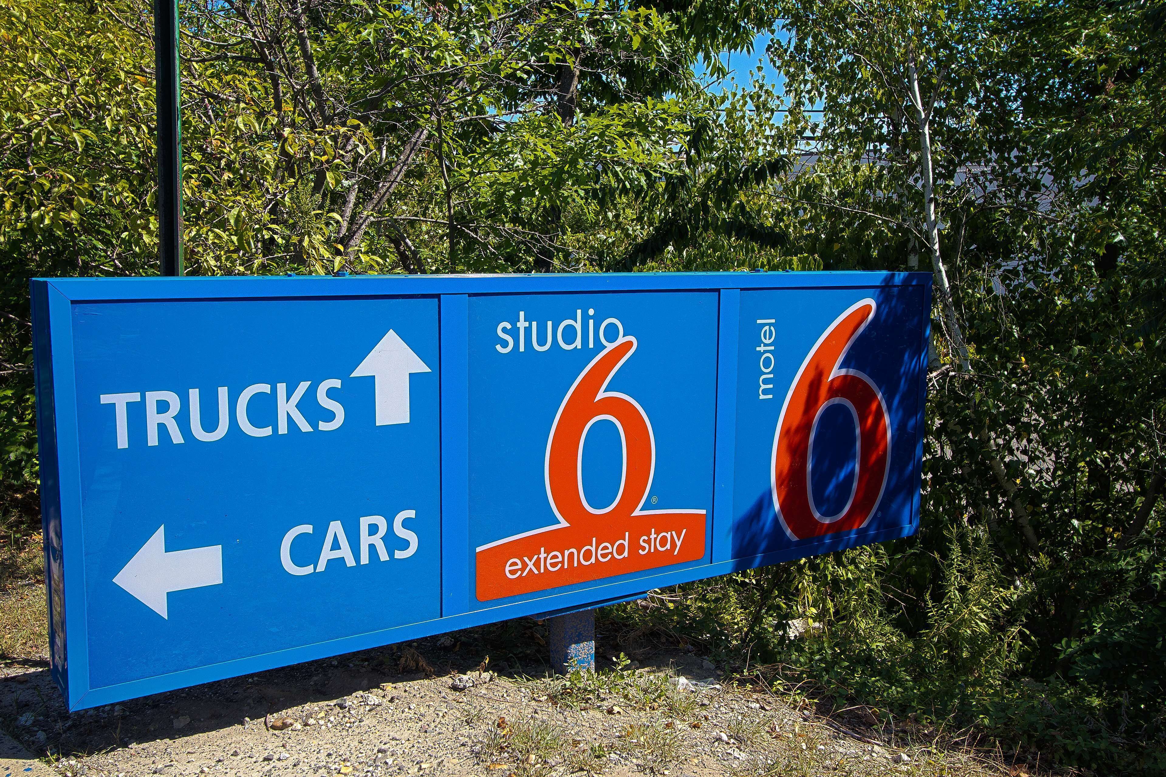 A directional sign for a motel with an arrow pointing to the left for cars and straight ahead for trucks.