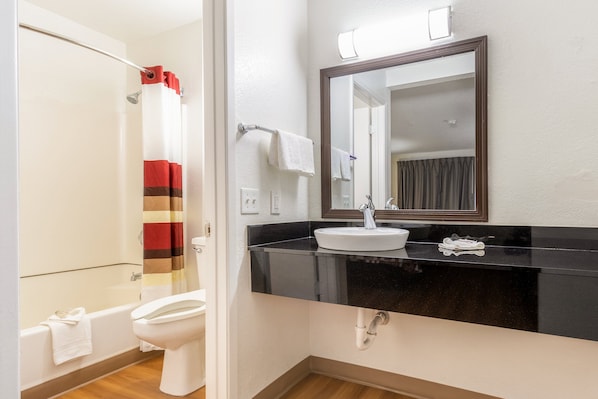 A bathroom with a white toilet, a black sink, and a mirror above it.