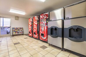 A row of vending machines with a Coca-Cola logo, a Scotsman branded refrigerator, and a display of travel brochures. - Red Roof Inn Phoenix - Midtown (Phoenix)