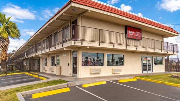 A hotel with a red-tiled roof, a balcony, and a sign for the Red Roof Inn.